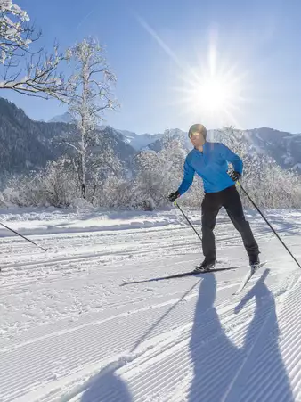Langläufer bei blauem Himmel und winterlicher Landschaft